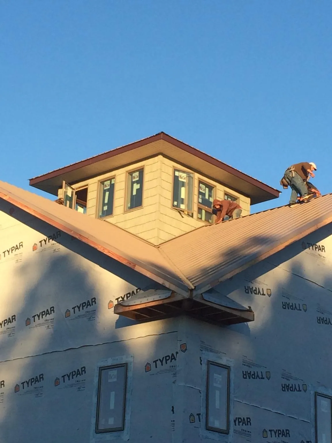 Roofers working around a rooftop cupola on a new metal roof at sunset — Roof Waterproofing in Guilford by Roofing Brothers